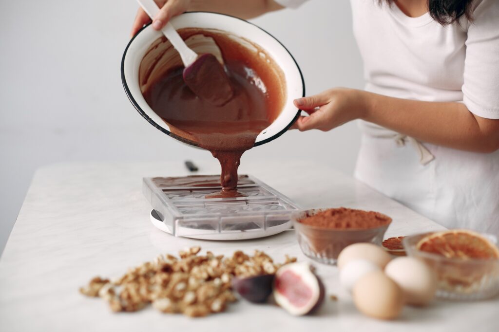 Chef in white clothes prepares a chocolate cake.