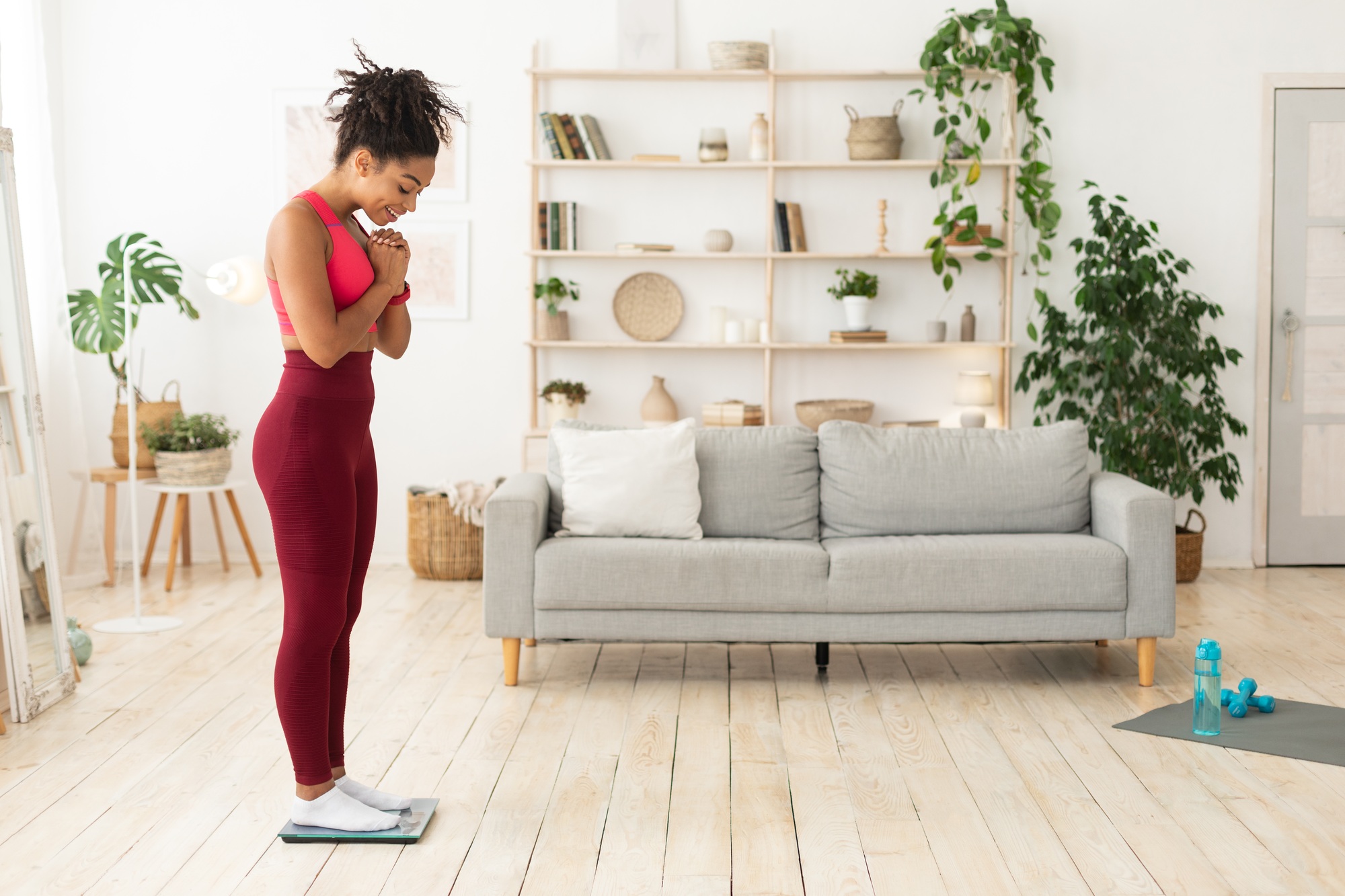 Happy Black Girl Weighing Herself On Weight-Scales Losing Weight Indoor