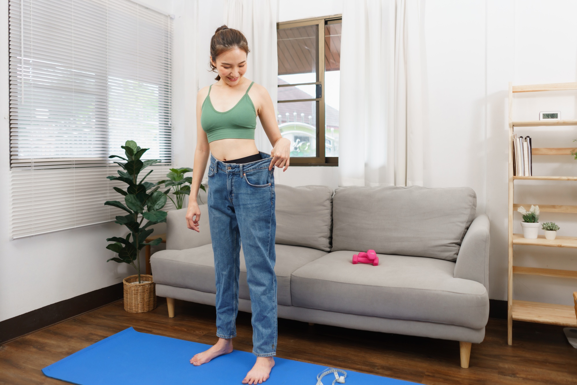 Healthy and weight loss concept, Young Asian woman in loose jeans when success with losing weight.