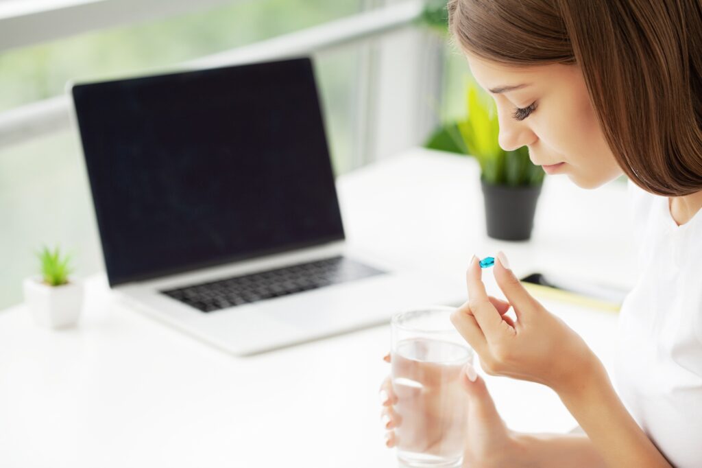 Healthy young woman holding pill glass of water